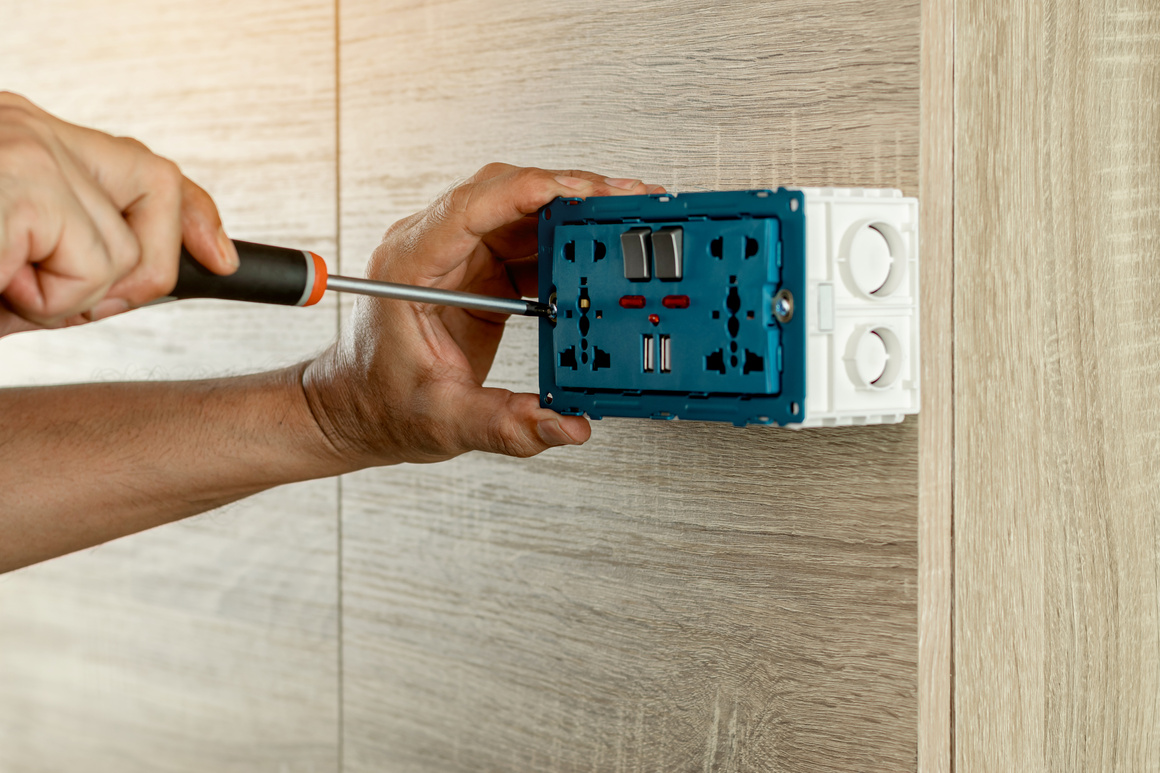 Electrician Is Using a Screwdriver to Install the Electric Power